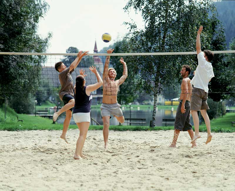 Junge Leute spielen Volleyball auf einem Beachvolleyballplatz